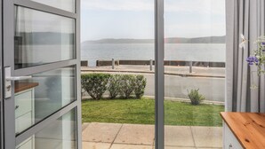Ein Zimmer mit einer Schiebeglastür, die auf einen Balkon mit Blick auf das Meer und eine entfernte Insel führt.