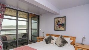 Ein Schlafzimmer mit Bett, Nachttisch, Schreibtisch und Stuhl. Ein Fenster bietet Blick ins Freie.