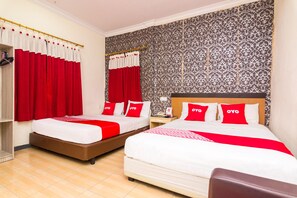 A hotel room with two beds, red and white bedding, a patterned wallpaper, and a wooden floor.