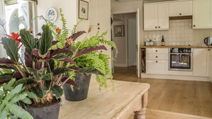 Et køkken med træskabe, en indbygget ovn og et spisebord med plantekasser.