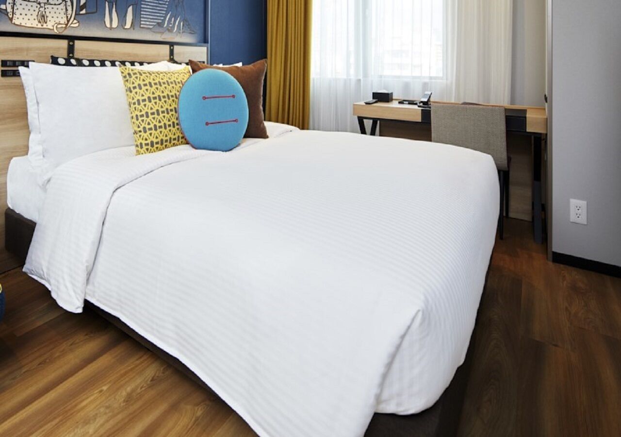 A hotel room with a large bed, a desk, and a window with curtains.