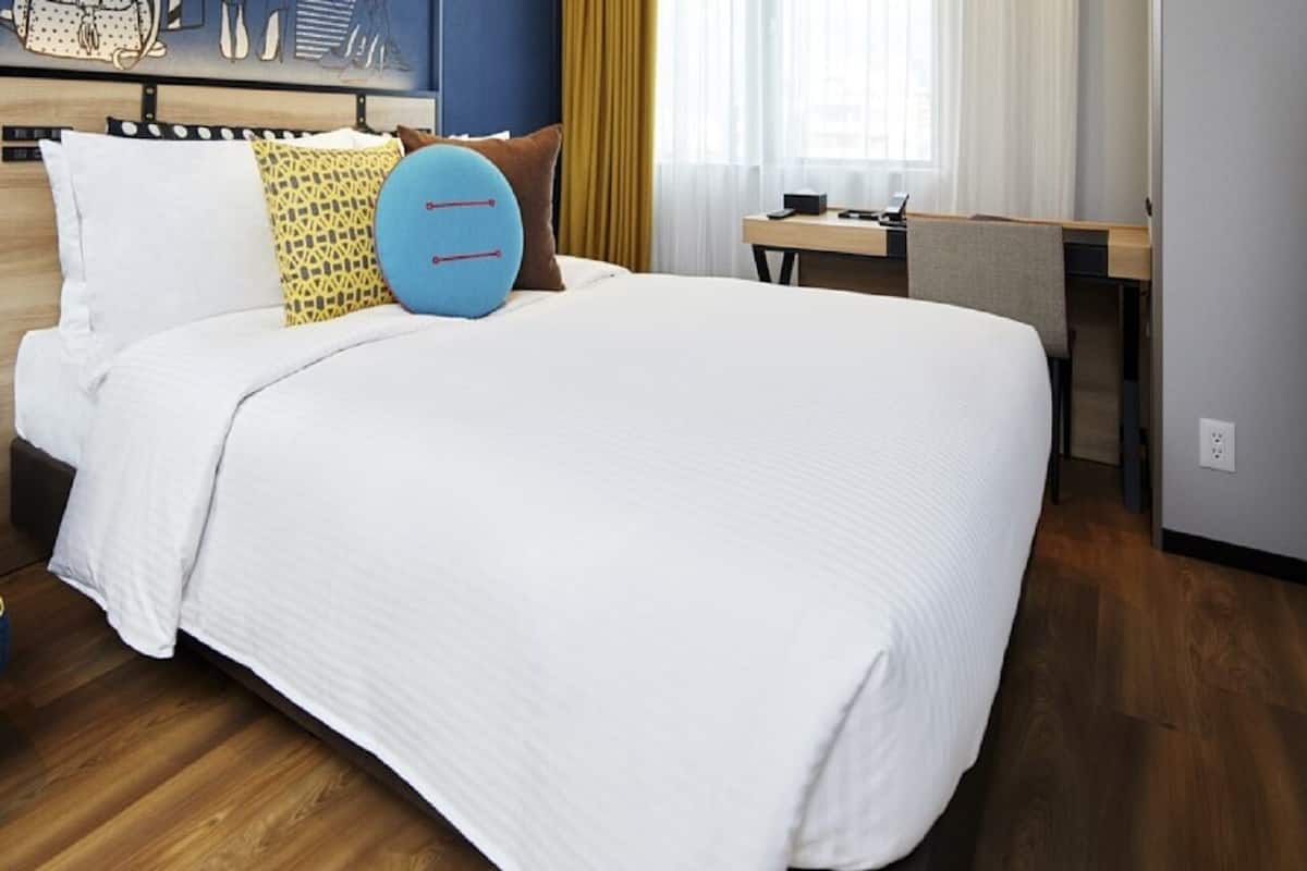 A hotel room with a large bed, a desk, and a window with curtains.
