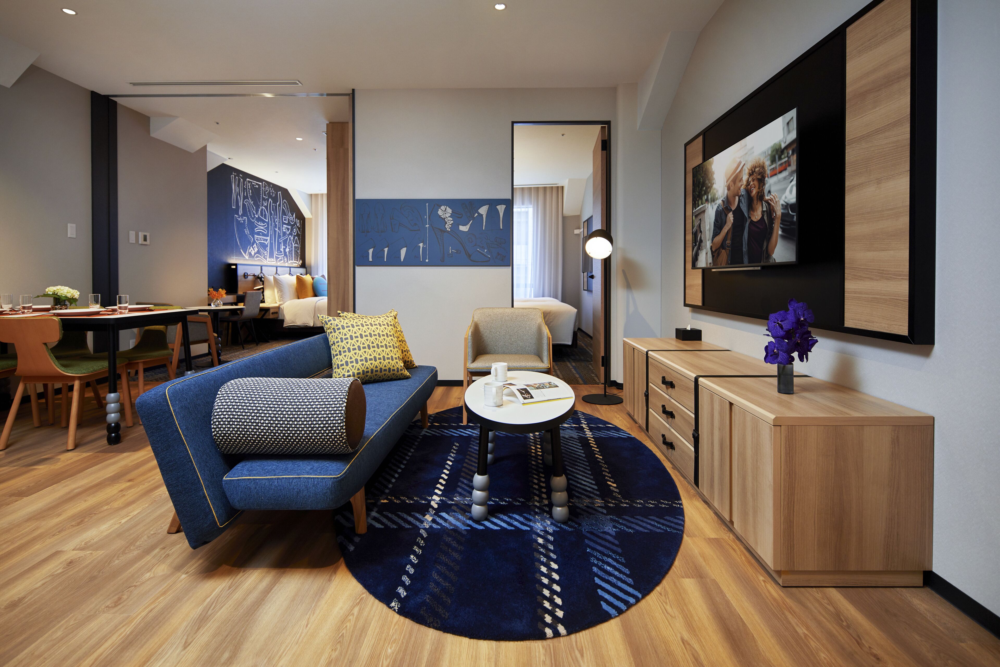 A modern living room with a blue sofa, a round coffee table, and a wooden cabinet.