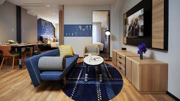 A modern living room with a blue sofa, a round coffee table, and a wooden cabinet.