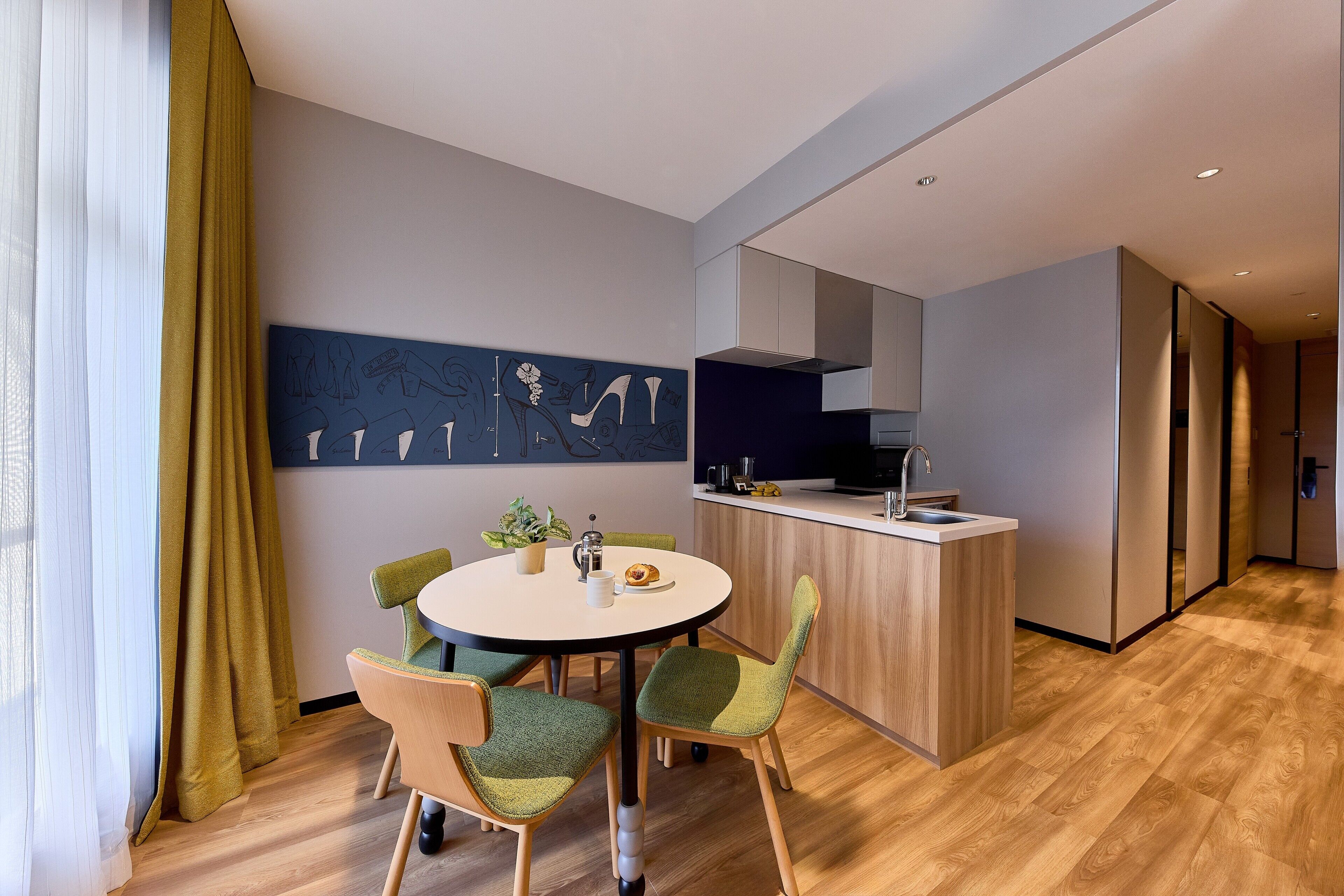 A modern kitchen with a central island, a dining area with a round table and chairs, and a large abstract artwork on the wall.