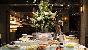Un bufé con diversos alimentos y un centro de mesa con flores blancas.