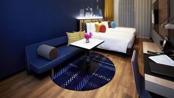 Une chambre d’hôtel comprenant un lit, un canapé, une petite table avec un vase de fleurs et un bureau avec une chaise.