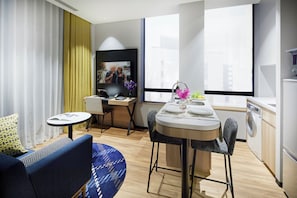 A modern hotel room with a dining area, a sofa, a small table, and a washing machine. - Citadines Namba Osaka (Osaka)
