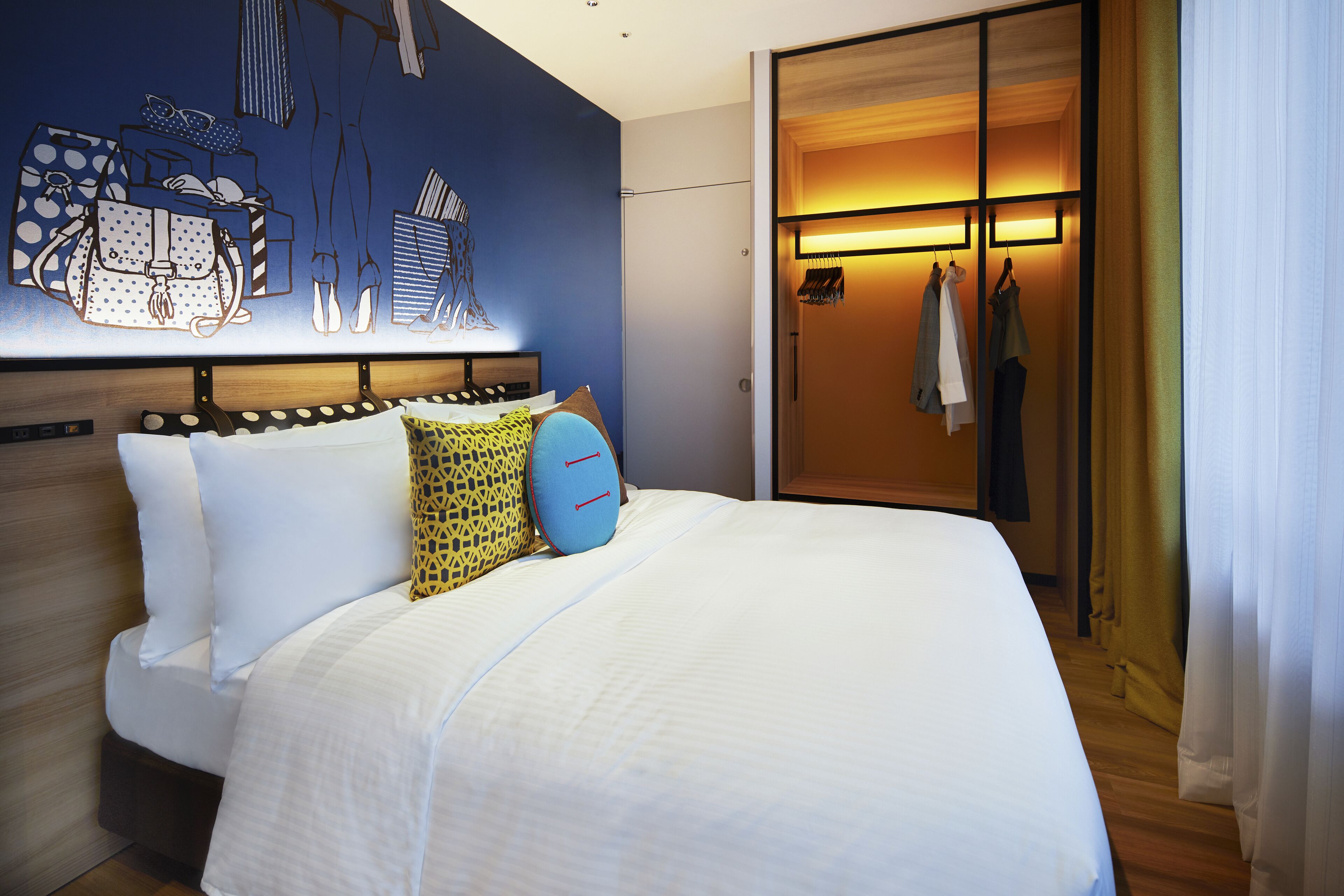 A hotel room with a bed, a wardrobe, and a wall with a design.
