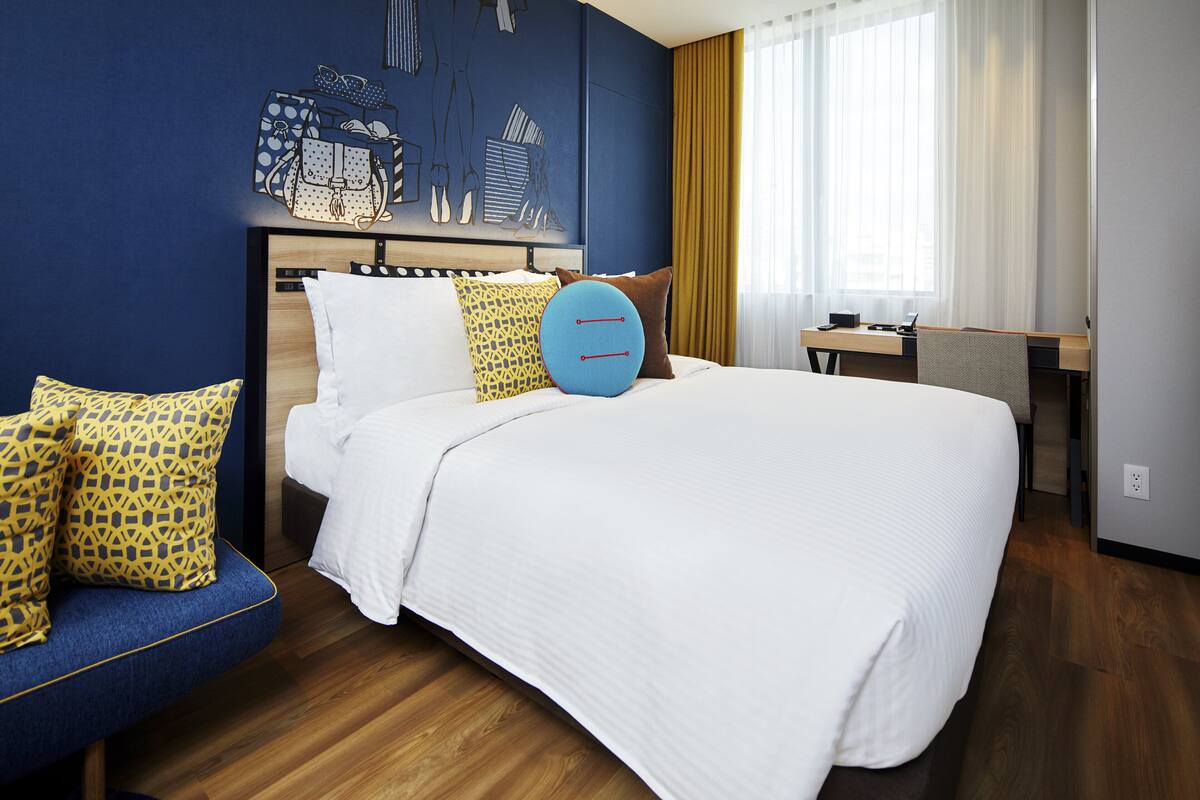 A hotel room with a large bed, a desk, and a chair.