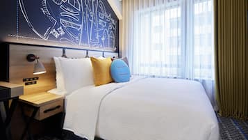 Habitación de hotel con una cama grande, una mesita de noche con lámpara, una pared con diseño de plano y una ventana con cortinas.