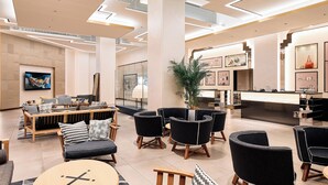 Un vestíbulo moderno con mostrador de recepción, área de estar con sofás y sillones, y obras de arte en las paredes.