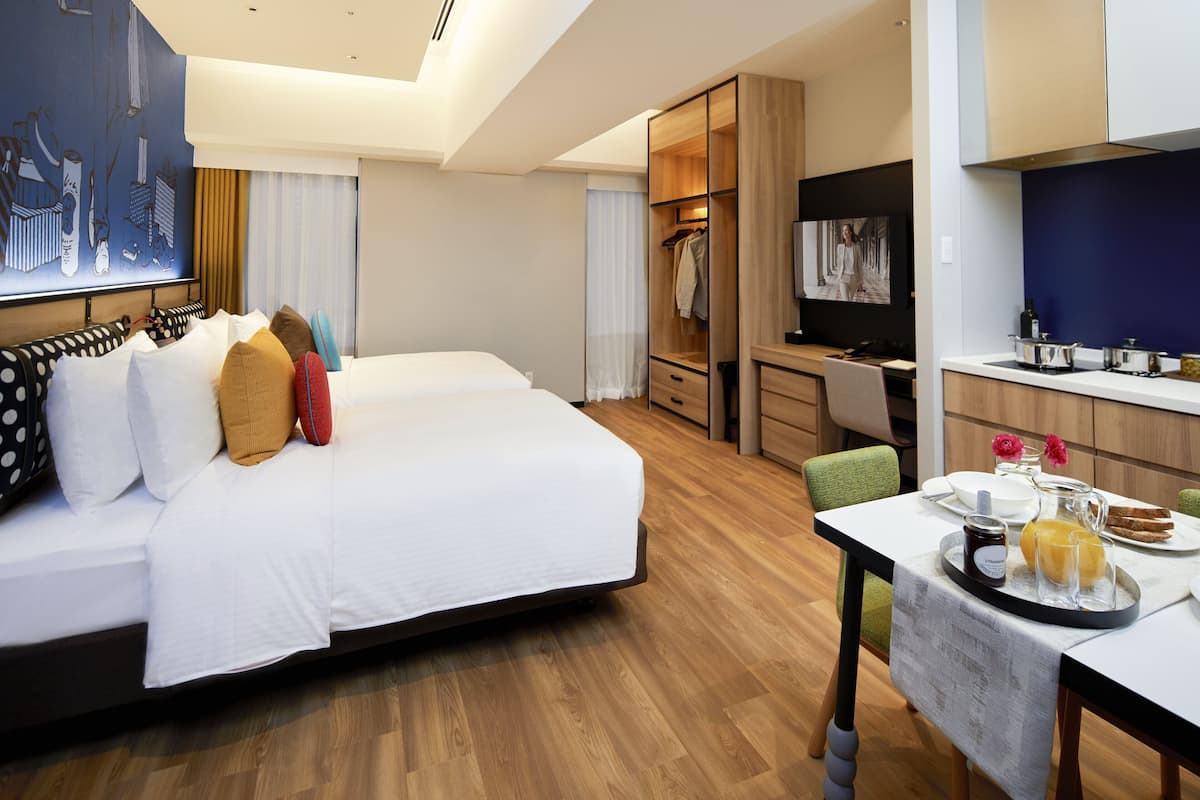 A hotel room with a bed, a desk, a dining table with breakfast, and a closet.