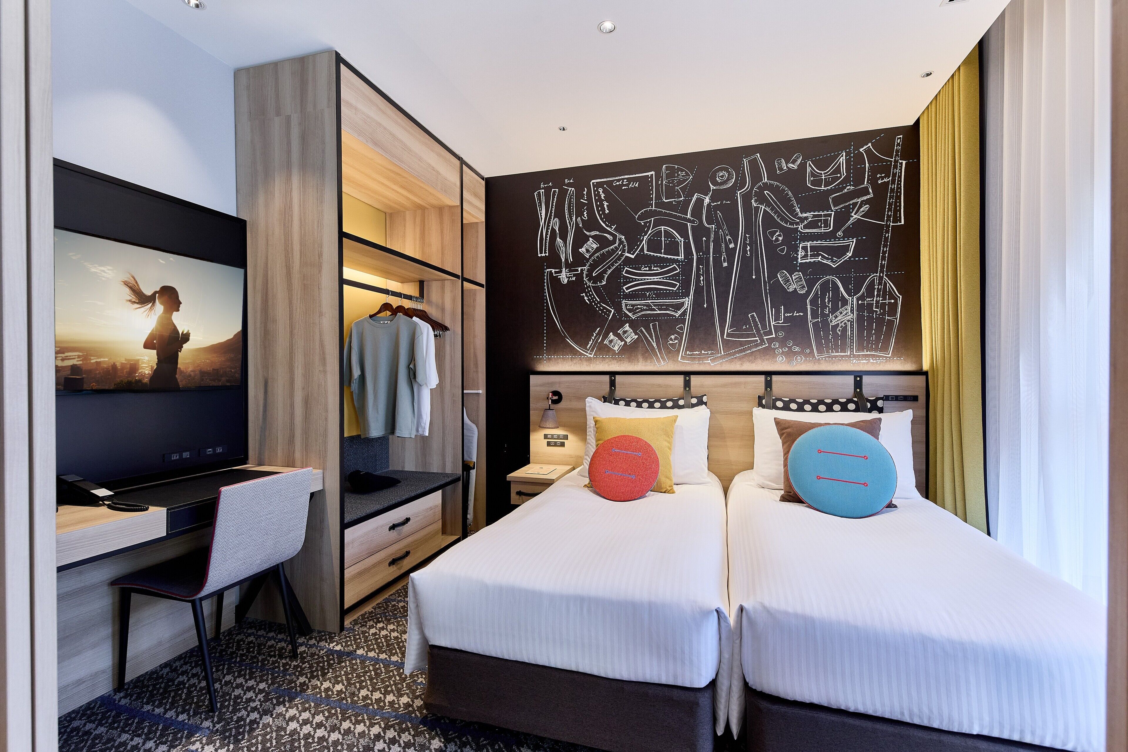 A hotel room with a bed, a desk, a TV, and a wall art piece.