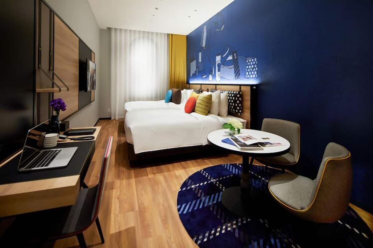 A hotel room with a bed, desk, chair, and a round table.