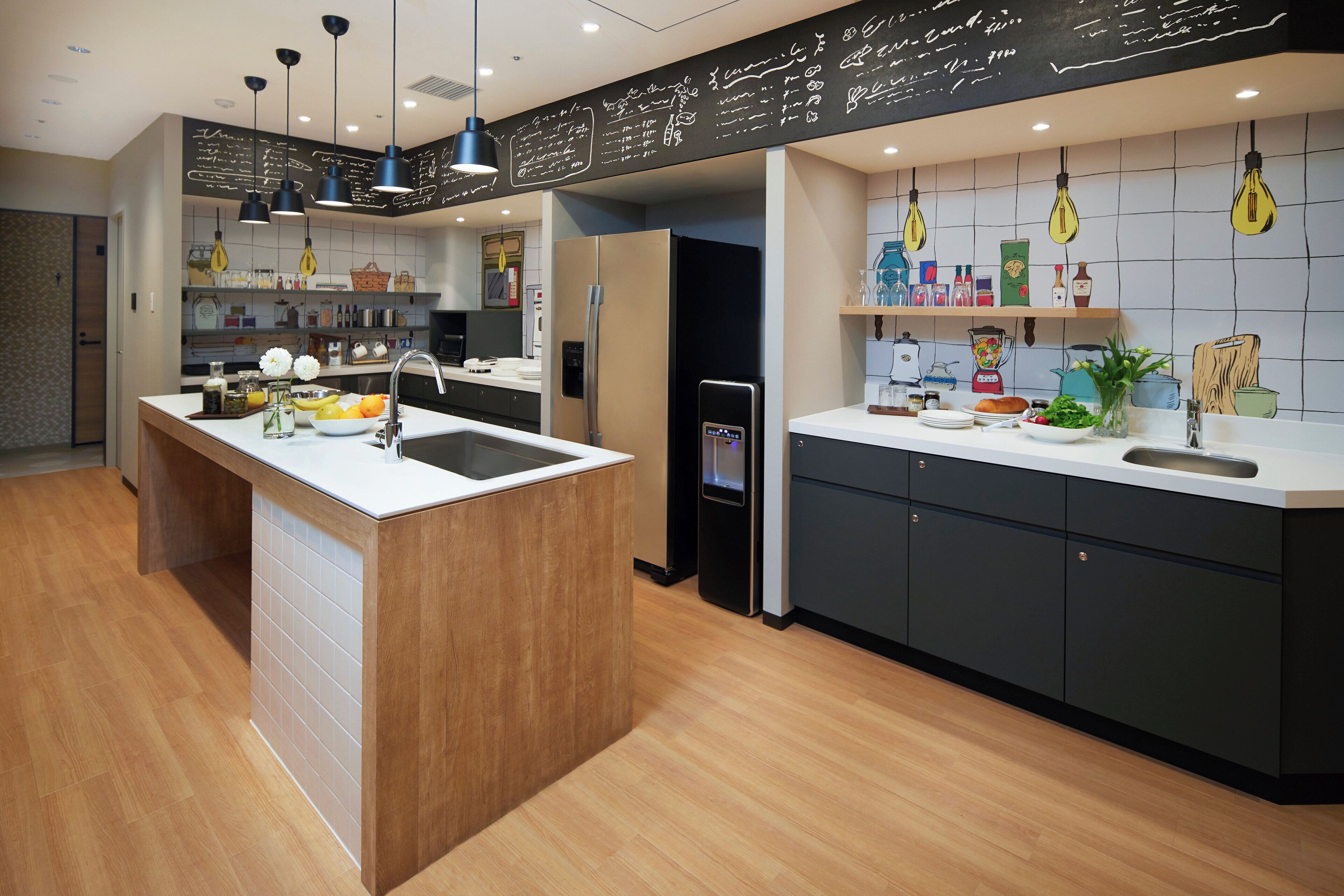A modern kitchen with a central island, black cabinets, and a chalkboard wall with writing.