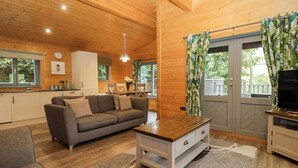 A cozy living room with a sofa, coffee table, and a TV stand. - Oak Lodge (Ulverston)