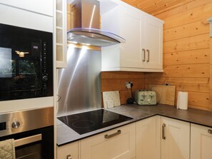 A modern kitchen with stainless steel appliances, a built-in oven, and a toaster. - Oak Lodge (Ulverston)