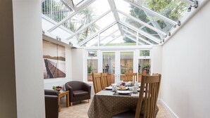 A cozy dining area with a table set for four, surrounded by wooden chairs and a glass ceiling. - Redcliff View Lodge (Weymouth)