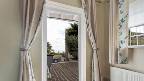 A room with a window overlooking a wooden deck and a garden. - Redcliff View Lodge (Weymouth)