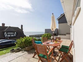 Un patio con mesa, sillas y vistas al mar.
