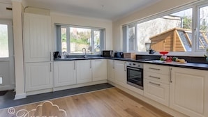 A spacious kitchen with white cabinetry, a black countertop, and a large window providing a view of the outdoors. - Seacliff (Bridport)