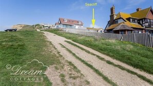 A coastal path leading to a seacliff with houses on the right.