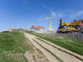 Un sendero costero que lleva a un acantilado con casas a la derecha.