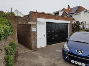 Eine Garage mit Wohnhäusern, einer weißen Tür, einer Backsteinmauer und einem Schild, das eine reservierte Parkberechtigung für eine bestimmte Gruppe anzeigt.