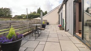 A patio with a table and chairs, potted plants, and a hose. - Underfell (Carnforth)