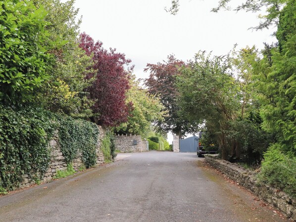 A narrow, paved road flanked by lush greenery and stone walls. - Underfell (Carnforth)
