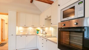Una cocina moderna con armarios blancos, horno de acero inoxidable y microondas integrado.