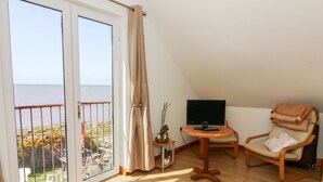 Une chambre avec un balcon, une télévision, une chaise et une petite table.