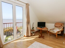 A room with a balcony, a TV, a chair, and a small table.