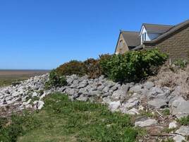A house with a stone wall, a garden, and a view of the sea.