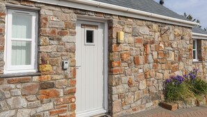 A stone house with a white door, a mailbox, and a small window. - Tyn Towyn - Bwthyn Carreg (Holyhead)