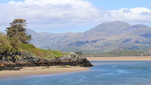 A coastal landscape with a sandy beach, rocky outcrops, and a solitary tree. - Sea View Apartment (Porthmadog)