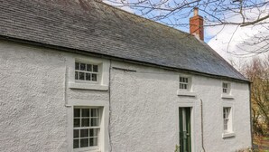 Un bâtiment blanc avec un toit gris, une porte verte et une petite fenêtre.