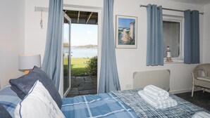 Un dormitorio con cama, una silla, un cuadro y vistas al exterior.
