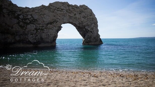A natural rock arch formation over a calm sea. - Ammonite Cottage (Portland)