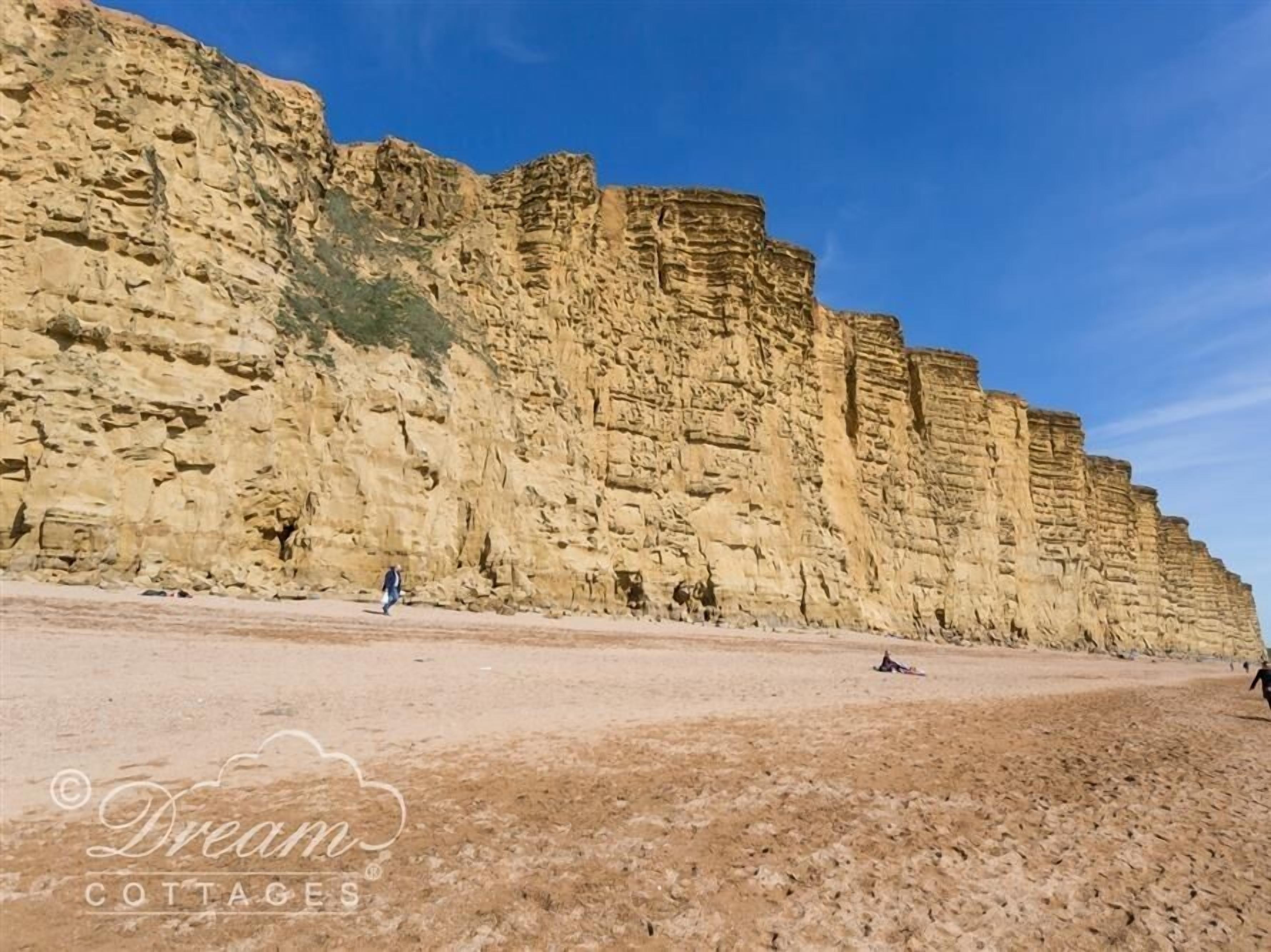 Une falaise côtière aux formations rocheuses en couches et à la plage de sable.