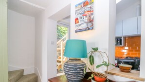 Eine moderne Küche mit einer Holzarbeitsplatte, einer blauen Lampe, einer gestreiften Vase und einem Blumentopf.