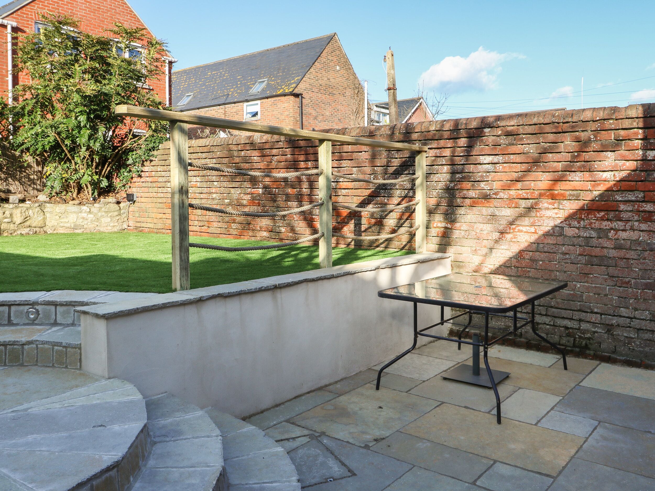 A patio with a stone table and a wooden swing set.