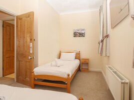 Un dormitorio con una cama de madera, una mesita de noche, un radiador y una puerta.