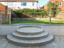 Una escalera de piedra conduce a un patio con vistas a un césped cuidado y un muro de piedra.