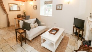 A living room with a sofa, coffee table, TV, and a dining area with a table and chairs.