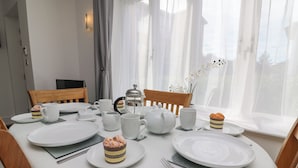 Ein Frühstückstisch mit weißen Tellern, Tassen, einem Teekessel und einer Kaffeekanne.