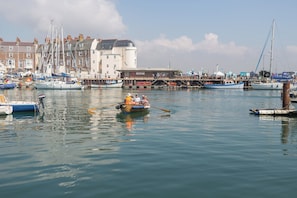 A harbor with boats docked, a pier with people, and a building with a sign.