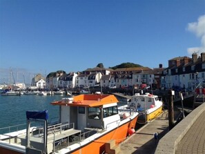 A harbor with boats docked, a waterfront promenade, and buildings with traditional architecture.