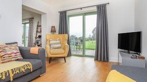 Una sala de estar con sofá, sillón y televisor.